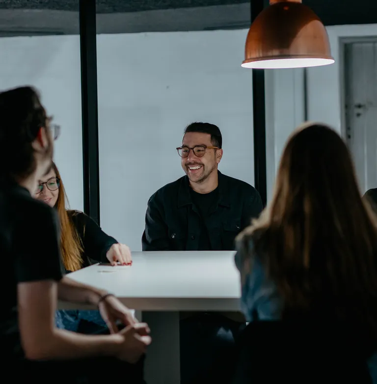 Time da Prod em reunião ao redor de uma mesa, em conversa descontraída.