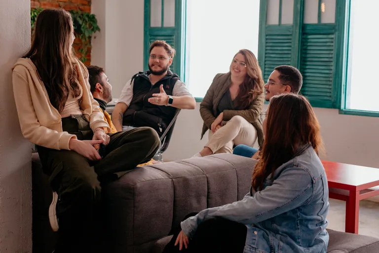 Seis pessoas do time da Prod conversando, sentadas em um sofá no escritório.